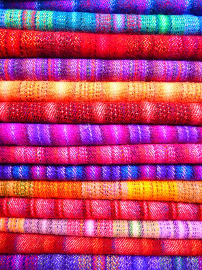 pink-and-blue-textile-near-yellow-textile-86757 Close-up of vibrant and colorful textiles stacked in layers, showcasing intricate patterns and designs.