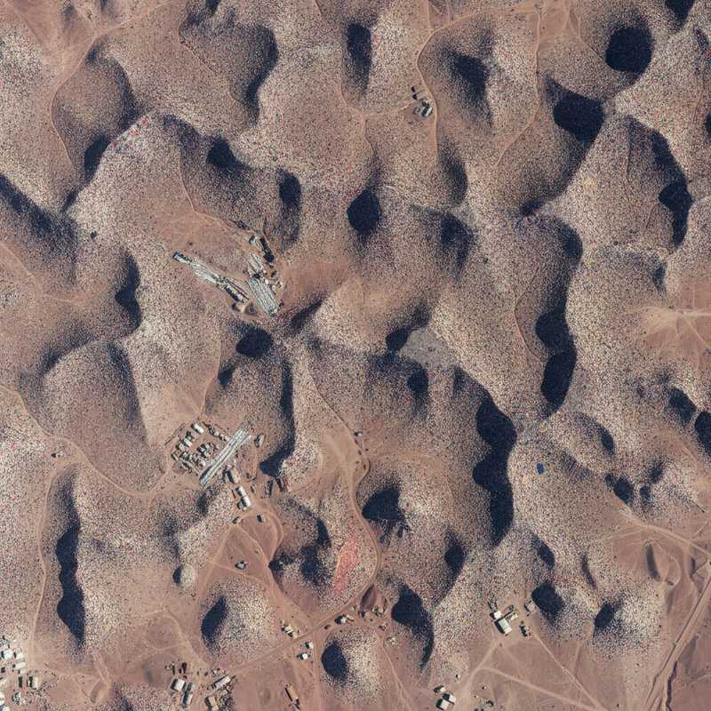 Luchtfoto van enorme hoeveelheid gedumpte kleding in de Atacama-woestijn in Chili, met kleurrijke textielhopen in droog woestijnlandschap